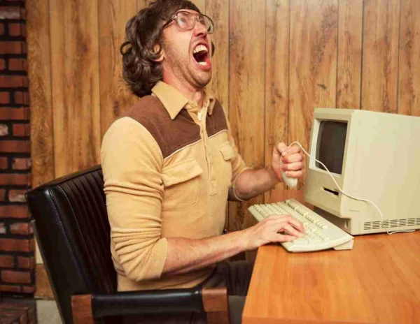 Frustrated marketer yelling at an old 1980s desktop computer, representing outdated digital marketing and SEO strategies.